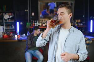 Night in bar. Portrait of cheerful men drinking beer at the bar photo