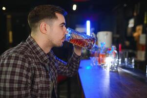 Night in bar. Portrait of cheerful men drinking beer at the bar photo