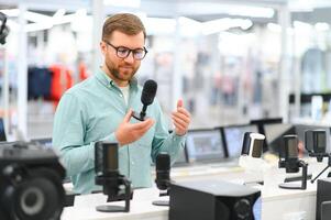 A man chooses a professional microphone to record a blog. Electronics store photo
