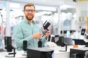 A man chooses a professional microphone to record a blog. Electronics store photo