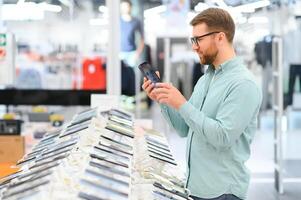 happy young man choosing a new mobile in a tech store photo