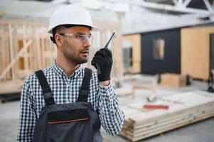 An engineer controls the production of modular houses and uses a walkie-talkie photo