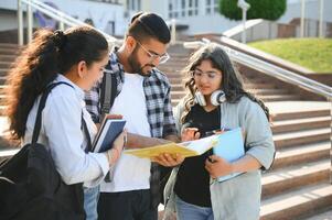 Portrait of three multi-ethnic university students embracing together standing in the campus photo
