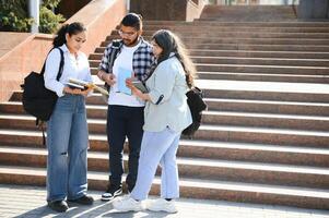 group of young students checking exam results or waiting for project approval on laptop at collage campus - concept of teamwork, bonding and friendship. photo