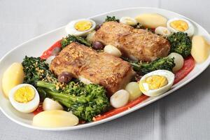Portuguese cod with eggs, broccoli and peppers on a plate photo