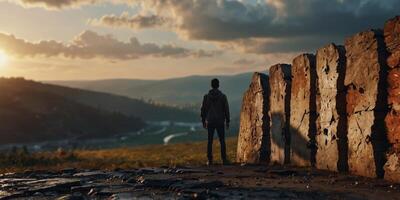A figure stands before a dramatic landscape through a broken wall. photo