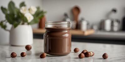 Chocolate hazelnut spread in a glass jar on a kitchen counter. photo