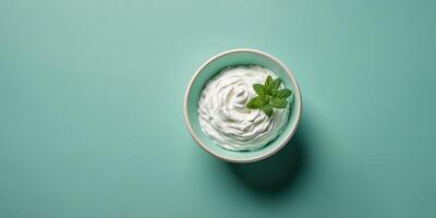Top view of bowl with white quark or cream on mint green background. photo