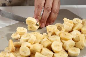 Hands of Old Female Slicing Banana photo