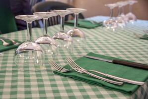 Table setting in a restaurant, close up of forks, knife on a napkin, and empty wine glasses. Served table photo