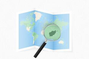 Enlarge Afghanistan with a magnifying glass on a folded map of the world. vector
