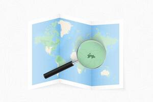 Enlarge Tajikistan with a magnifying glass on a folded map of the world. vector