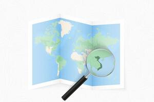 Enlarge Vietnam with a magnifying glass on a folded map of the world. vector