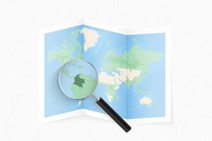 Enlarge Colombia with a magnifying glass on a folded map of the world. vector