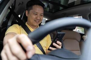 Cheerful arab driver man texting on smartphone while driving car. transport, vehicle and technology concept photo