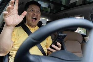 Terrified businessman having a car accident while using cell phone. Oh my God, I am going to crash. photo