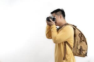 Smiling Asian photographer carrying a backpack taking pictures with a camera Isolated studio, white background. photo