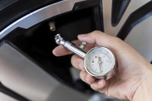 Close-up of a tire pressure gauge on a new wheel at a tire service workshop. Hand man checking air pressure air car tire. photo