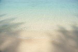 Sea wave and soft sandy with shadow of beach tree. photo