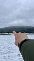A finger of a hand points to a mountain peak in winter. photo
