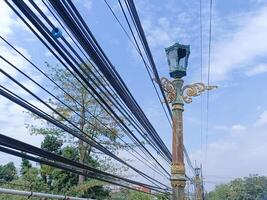 lighting lamp for street with wires running between it and blue sky background photo