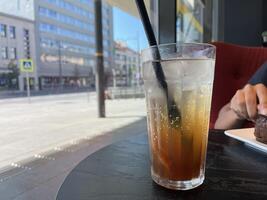 A glass of sparking iced tea on a cafe table with city view. photo