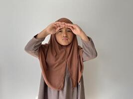 Asian Muslim little girl wearing hijab with both hand in forehead show sad expression. photo