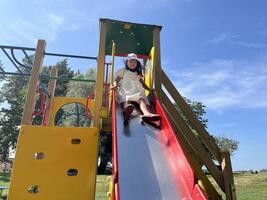 Happy Asian little girl playing slide in playground. Kids having fun in playground. photo