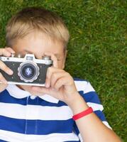 Happy smiling little boy with retro vintage camera photo