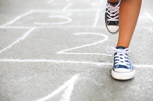 Kid playing hopscotch on playground outdoors photo