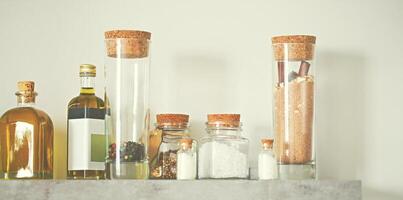 Selective focus of arranged jars with various spices and olive oil on kitchen shelf photo