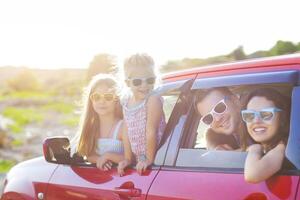 Portrait of a smiling family with two children at beach in the car photo