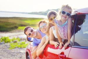 Portrait of a smiling family with two children at beach in the car photo