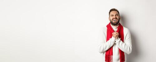 Christmas holidays and New Year concept. Man in need begging for help, pleading and looking miserable, apologizing for something, standing over white background photo