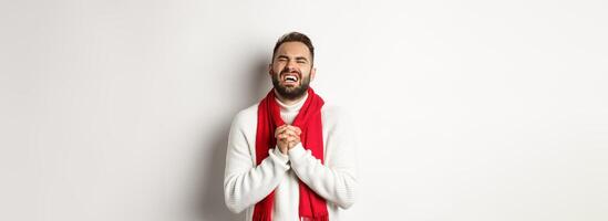 Christmas holidays and New Year concept. Man in need begging for help, pleading and looking miserable, apologizing for something, standing over white background photo