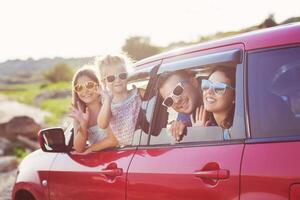 Portrait of a smiling family with two children at beach in the car photo
