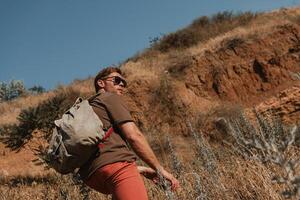 Confident male adventurer with backpack enjoying the view while hiking in mountains photo