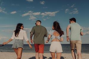 Rear view of happy young people running to the sea by the beach photo