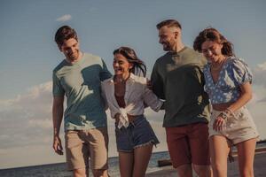 Group of carefree young people bonding and smiling while walking by the beach together photo