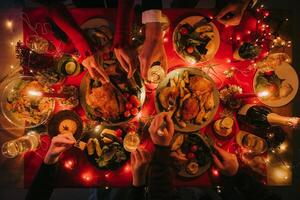 Top view of people enjoying variety of festive dishes while having Christmas dinner at the decorated table photo