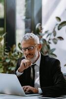 Confident mature man in formalwear using computer while working in the modern office photo