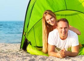Happy young couple camping on the beach photo