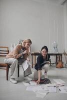 Two confident female fashion designers examining sketches while working in workshop photo