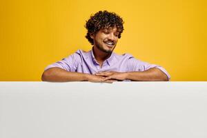 Handsome Indian man looking at the copy space and smiling against yellow background photo