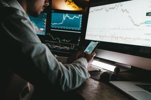 Close-up of male financial broker using technologies while analyzing stock market graphs and charts in office photo