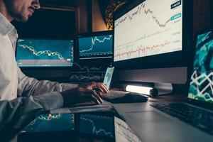 Close-up of financial broker working on computer while trading on stock market in night office photo