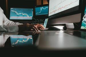 Close-up of male trader typing on computer keyboard while trading on stock market in night office photo