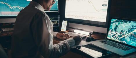 Close-up male trader analyzing stock market data while sitting at the office workstation with multiple computers photo