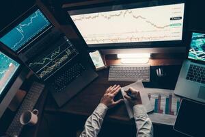 Top view of male trader analyzing stock market data while sitting at the office workstation with multiple computers photo