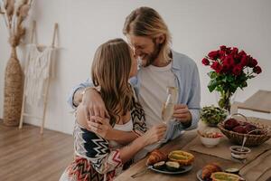 Top view of young couple embracing and toasting with champagne while celebrating anniversary at home photo